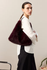 Model holding the Wine faux fur bag with leather handle by Helen Moore