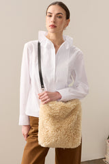 Model holding the cream faux sheepskin Barrel Tote Bag by Helen Moore