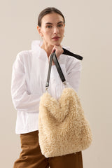 Model holding the cream faux sheepskin Barrel Tote Bag by Helen Moore