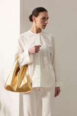 Model holding Gold Mini Leather Triangle Bag by Helen Moore