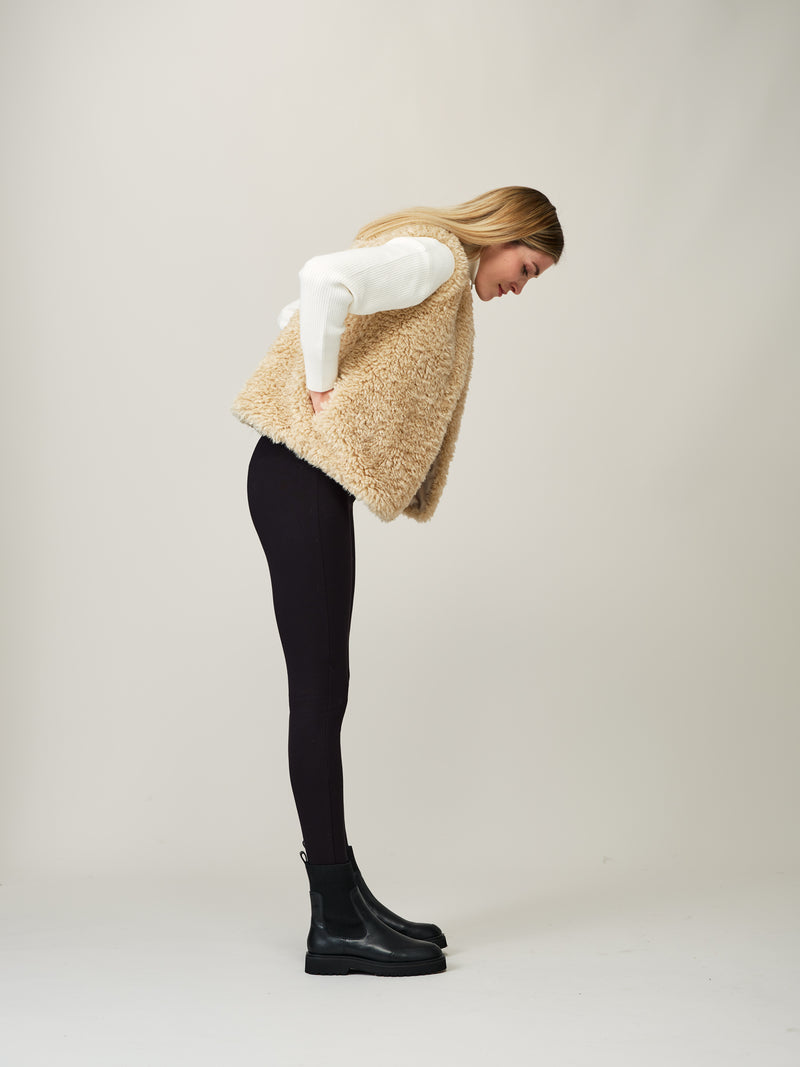 Model wearing a cream faux sheepskin gilet by Helen Moore
