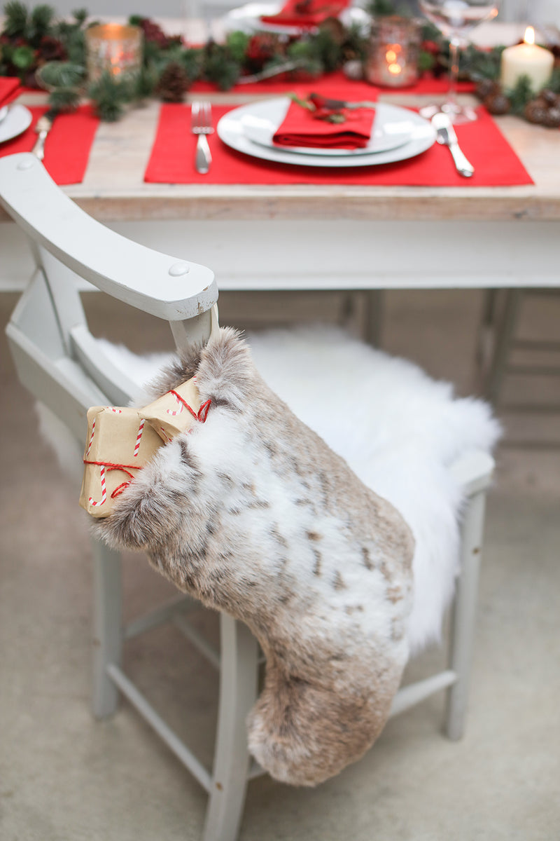 Faux fur Christmas stocking by Helen Moore hanging on a chair.