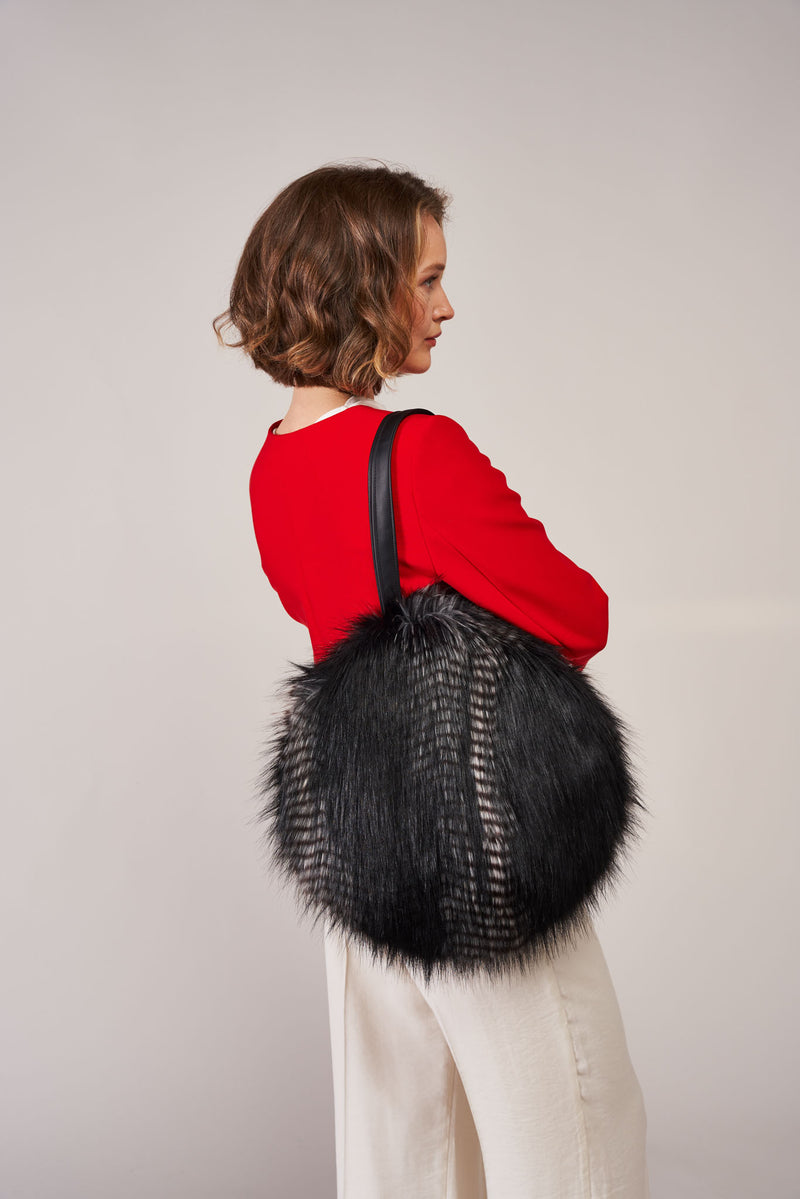 Model carrying a round bag by Helen Moore in Black Quail faux fur