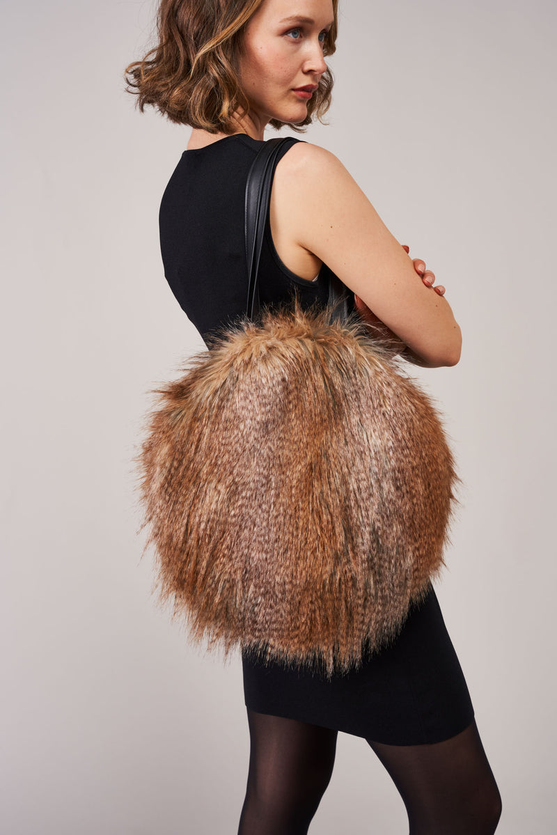 Model carrying a round bag by Helen Moore in Siberian Wolf faux fur