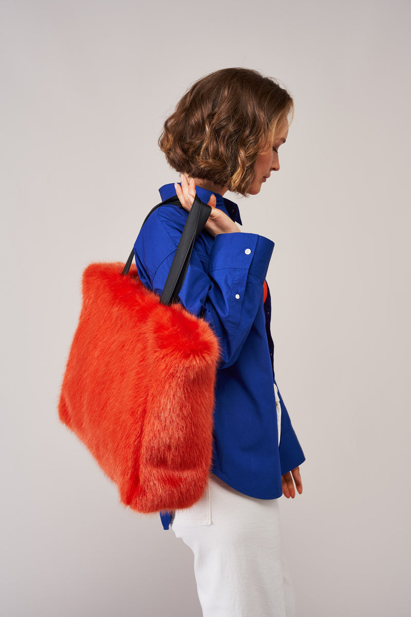 Model holding a large orange faux fur tote bag by Helen Moore